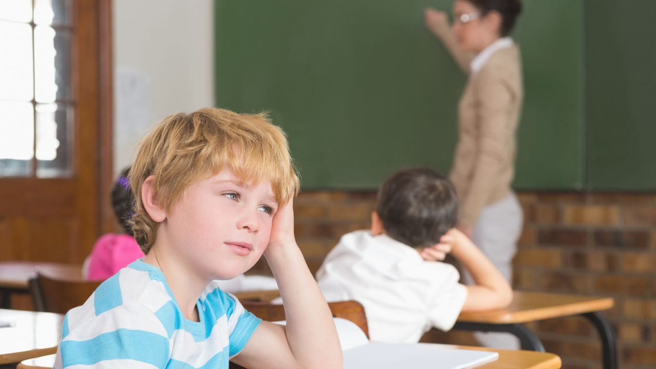 Boy resting his head on his hand at a school desk during class