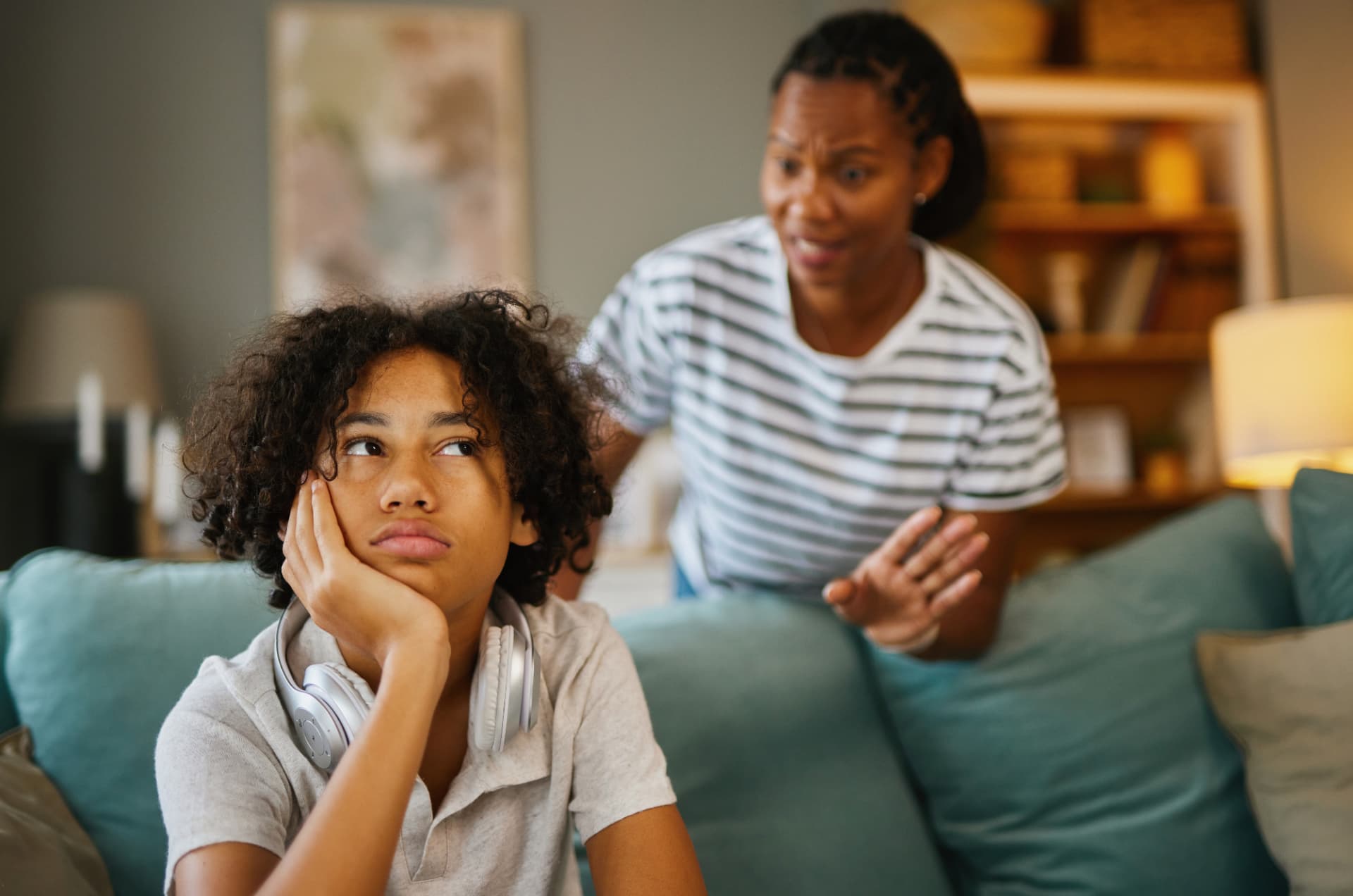 Tired child on the couch after school while a parent talks to them
